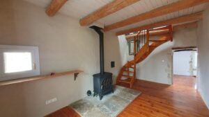 Salon chaleureux avec poêle à bois dans une maison de village à Saint-Dionisy